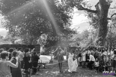 Un couple en tenue de mariage pose devant des lumières colorées dans une ambiance festive.