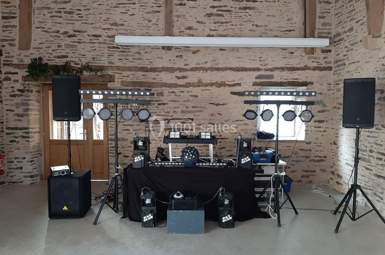 Installation de matériel de sonorisation et d'éclairage dans une salle en pierre avec des équipements sur une table.