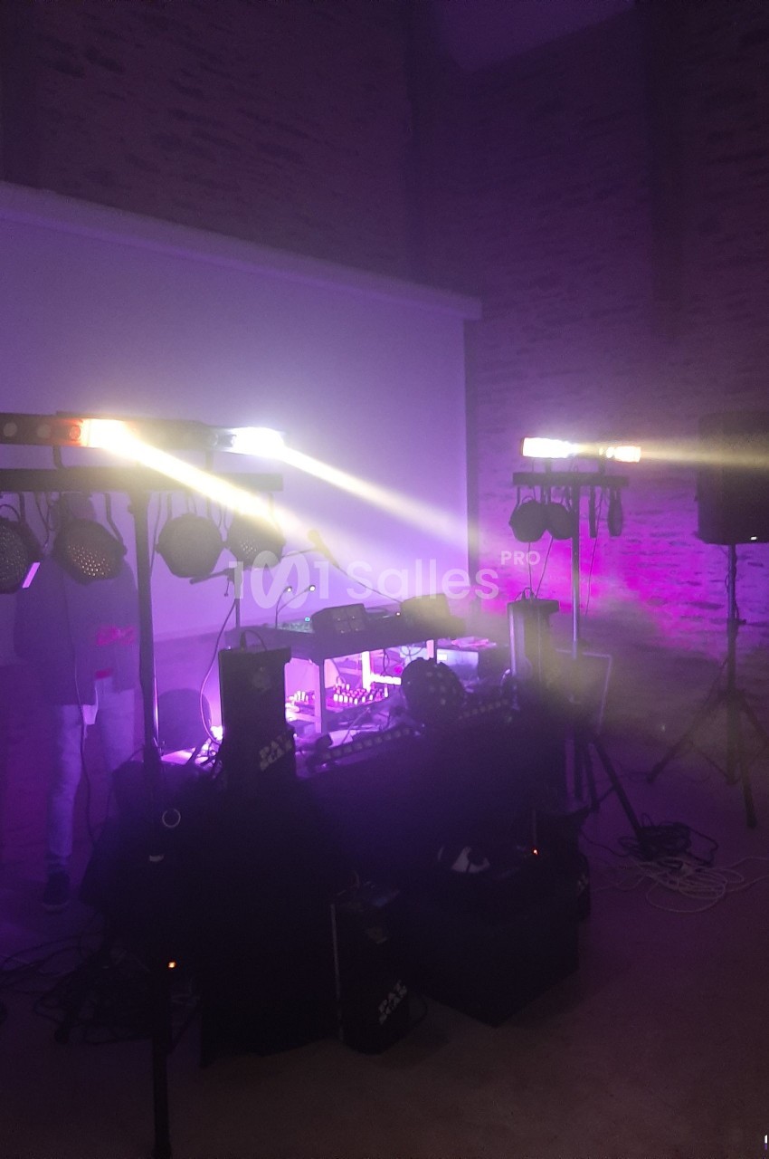 Équipement de sonorisation et éclairage installé dans une salle avec ambiance lumineuse violette.