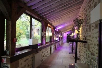Ruelle pavée bordée de fleurs, avec un puits en pierre et des bâtiments anciens sous un ciel ensoleillé.