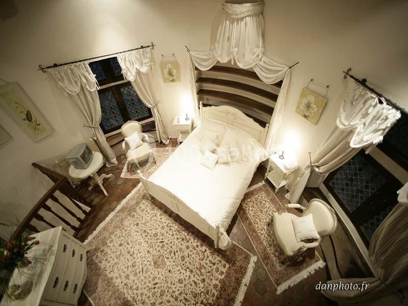 Chambre lumineuse avec lit double, mobilier blanc, tapis décoratif et rideaux élégants dans un style classique.