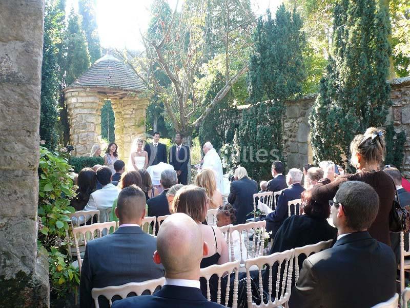 Cérémonie de mariage en plein air dans un jardin, avec des invités assis et un officiant devant les mariés.