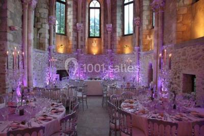 Ruelle pavée bordée de fleurs, avec un puits en pierre et des bâtiments anciens sous un ciel ensoleillé.