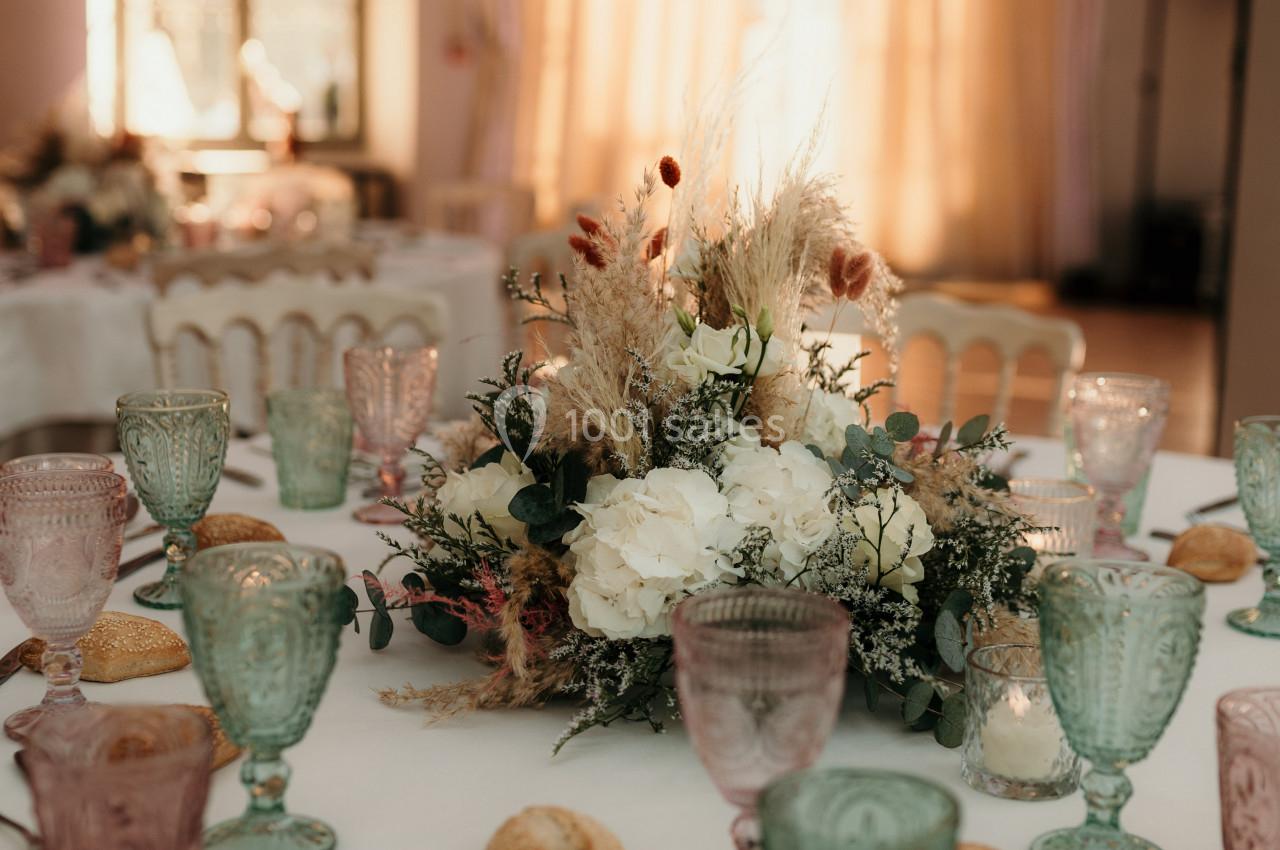 Table dressée avec vaisselle colorée, bouquet floral central, pains individuels et lumière naturelle en arrière-plan.