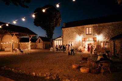 Ruelle pavée bordée de fleurs, avec un puits en pierre et des bâtiments anciens sous un ciel ensoleillé.