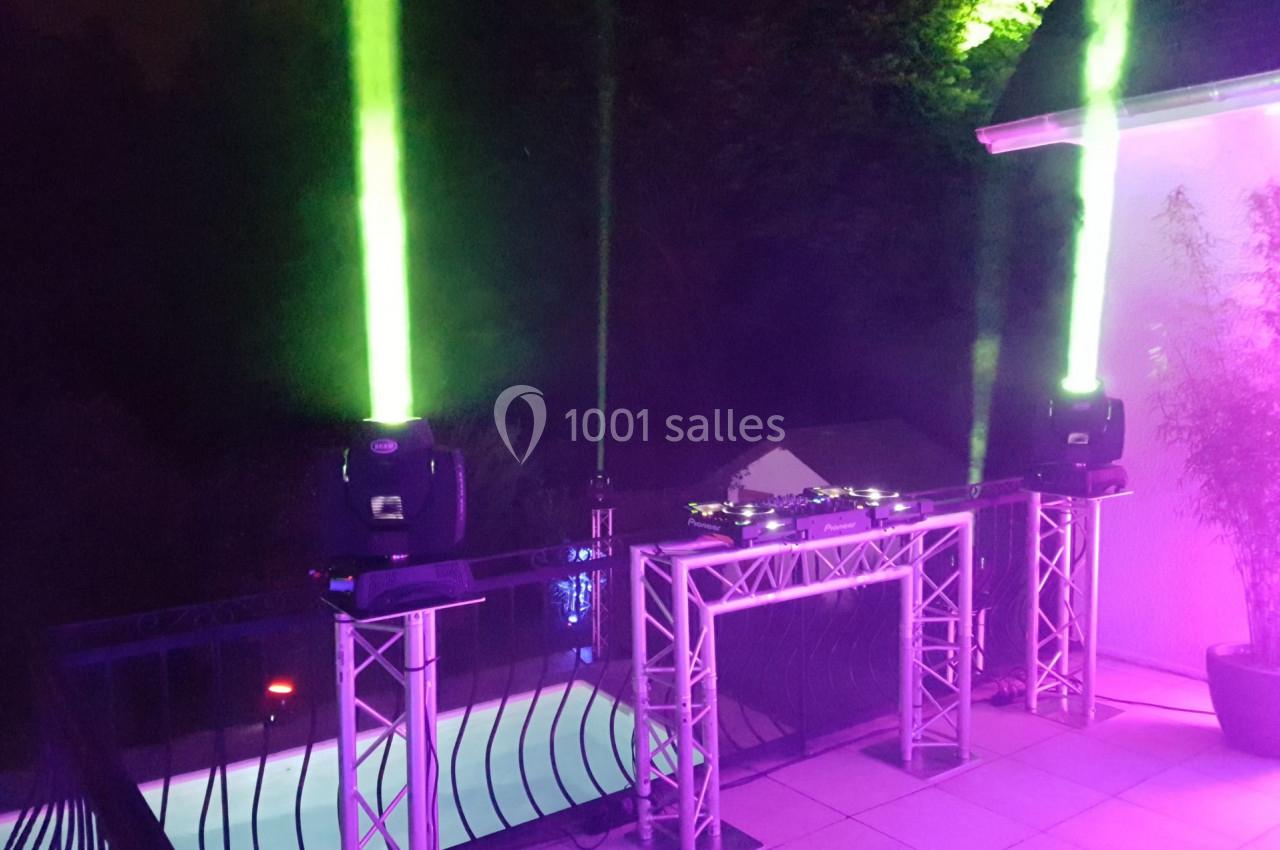 Installation de matériel de sonorisation et d'éclairage avec projecteurs verts sur une terrasse près d'une piscine.