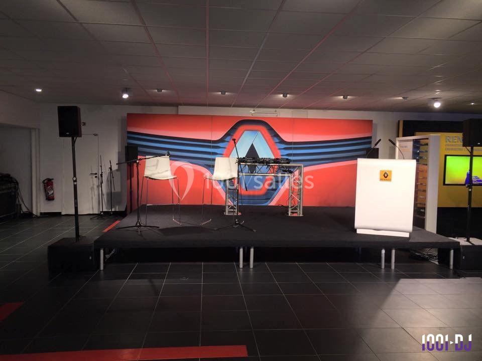 Scène intérieure avec deux chaises hautes, un pupitre et un fond décoratif rouge et bleu.