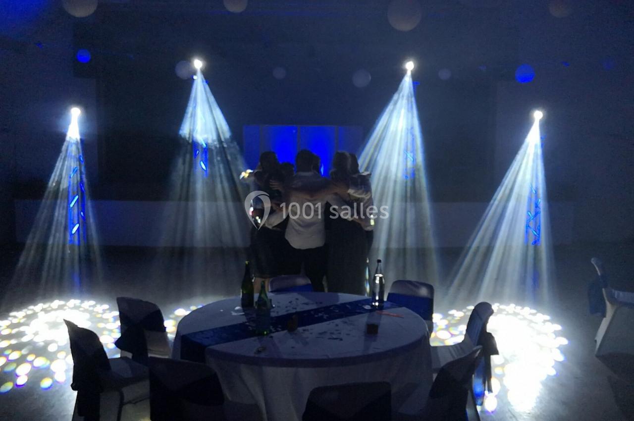 Quatre personnes s'embrassent au centre d'une piste de danse éclairée par des projecteurs et des jeux de lumière.