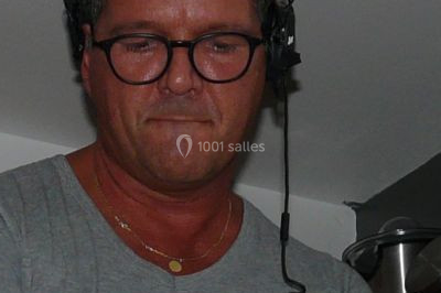 Un homme portant un casque audio mixe de la musique sur un ordinateur portable et un équipement de DJ.