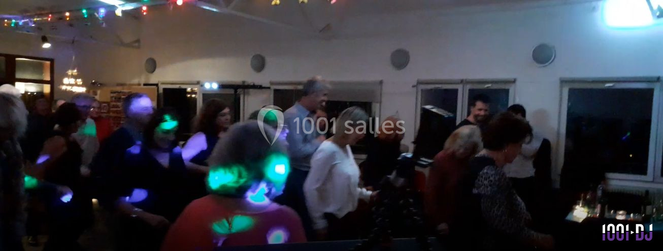 Des personnes dansent dans une salle éclairée par des lumières colorées, créant une ambiance festive.