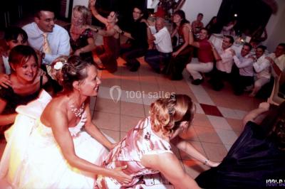 Des personnes dansent sous des guirlandes lumineuses dans une salle décorée pour une fête.