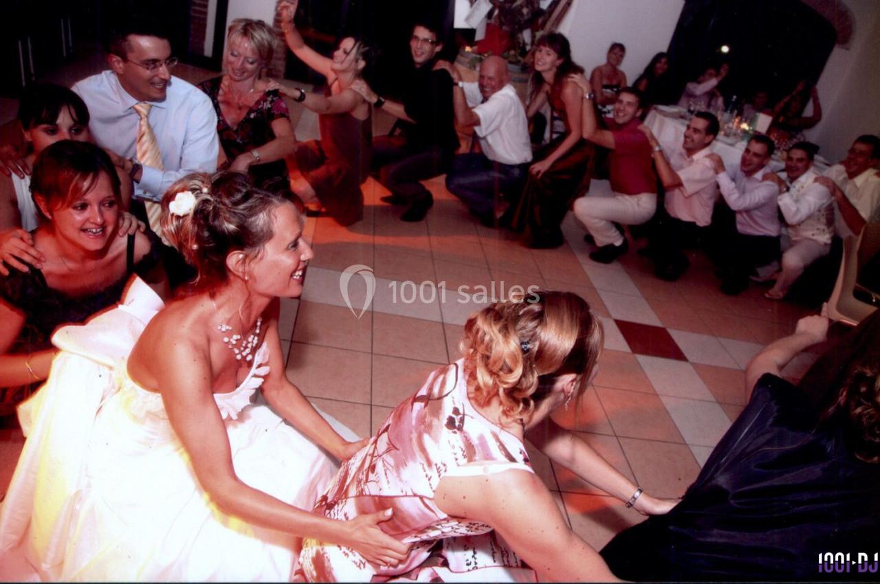 Des invités dansent en file indienne lors d'une fête, dans une salle éclairée par des lumières chaudes.