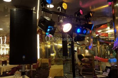 Des personnes dansent sous des guirlandes lumineuses dans une salle décorée pour une fête.