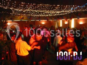 Des personnes dansent sous des guirlandes lumineuses dans une salle décorée pour une fête.