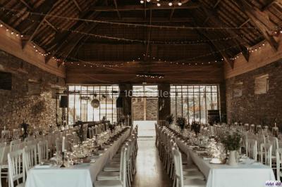 Portrait en noir et blanc d'un homme souriant avec des cheveux bouclés et une moustache, sur un fond flou naturel.