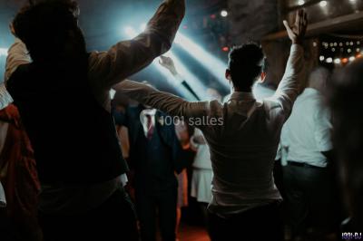 Portrait en noir et blanc d'un homme souriant avec des cheveux bouclés et une moustache, sur un fond flou naturel.
