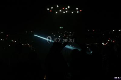 Portrait en noir et blanc d'un homme souriant avec des cheveux bouclés et une moustache, sur un fond flou naturel.