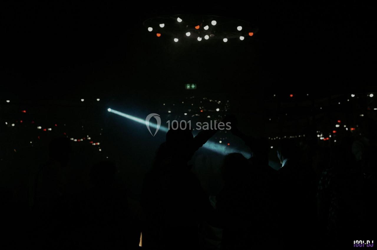 Des silhouettes dansent sous une lumière tamisée avec des spots lumineux en arrière-plan.