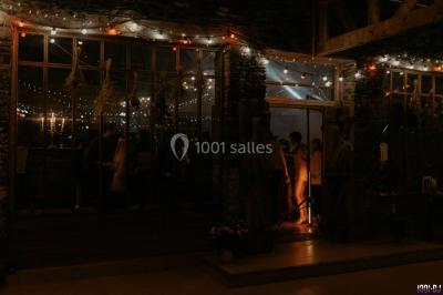 Portrait en noir et blanc d'un homme souriant avec des cheveux bouclés et une moustache, sur un fond flou naturel.