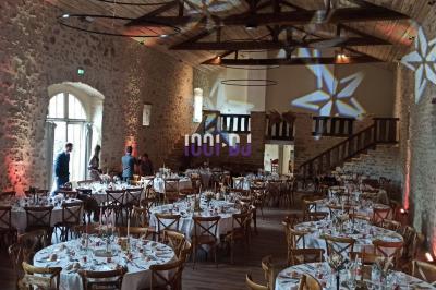 Salle de réception avec scène éclairée par des projecteurs orange, décorée de ballons suspendus.