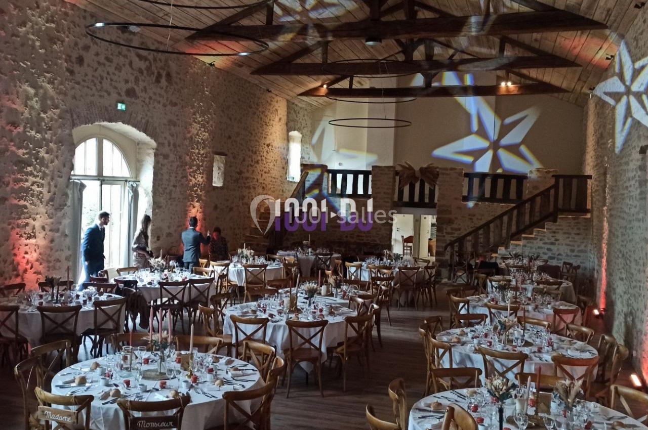 Salle de réception en pierre avec tables dressées pour un événement, éclairages décoratifs en étoile au plafond.