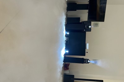 Salle de réception avec scène éclairée par des projecteurs orange, décorée de ballons suspendus.