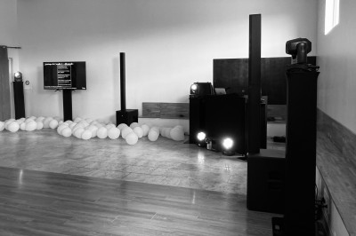 Salle de réception avec scène éclairée par des projecteurs orange, décorée de ballons suspendus.