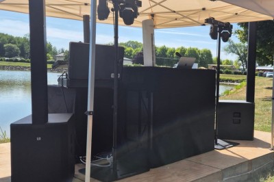 Salle de réception avec scène éclairée par des projecteurs orange, décorée de ballons suspendus.