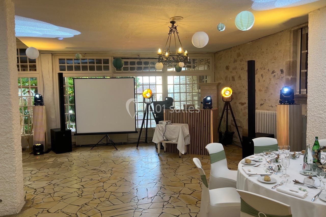 Salle de réception décorée avec des lanternes suspendues, un écran de projection et des équipements d'éclairage.