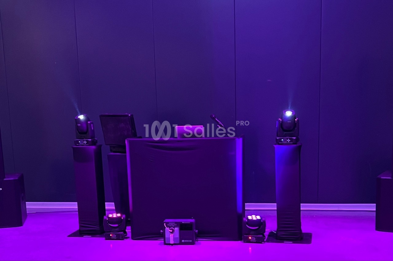 Installation de matériel de sonorisation et d'éclairage avec une table de mixage dans une ambiance lumineuse violette.