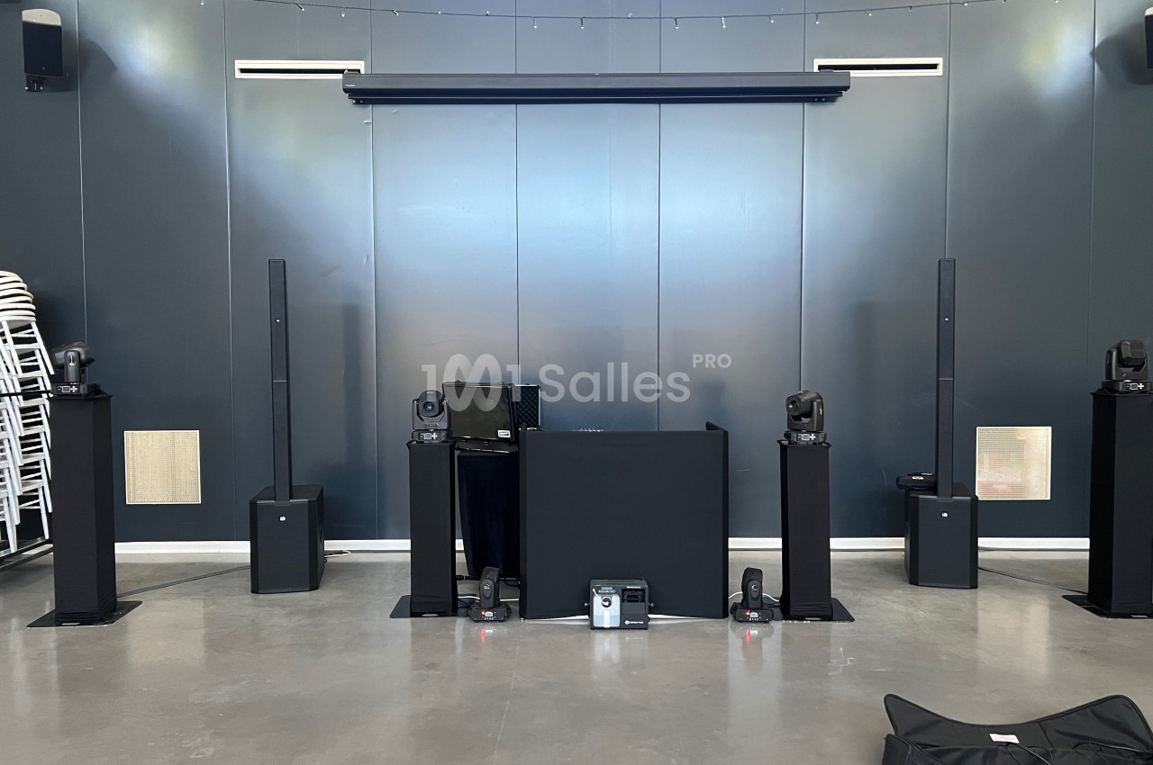 Installation de matériel audio et éclairage avec enceintes, projecteurs et table de mixage dans une salle sombre.