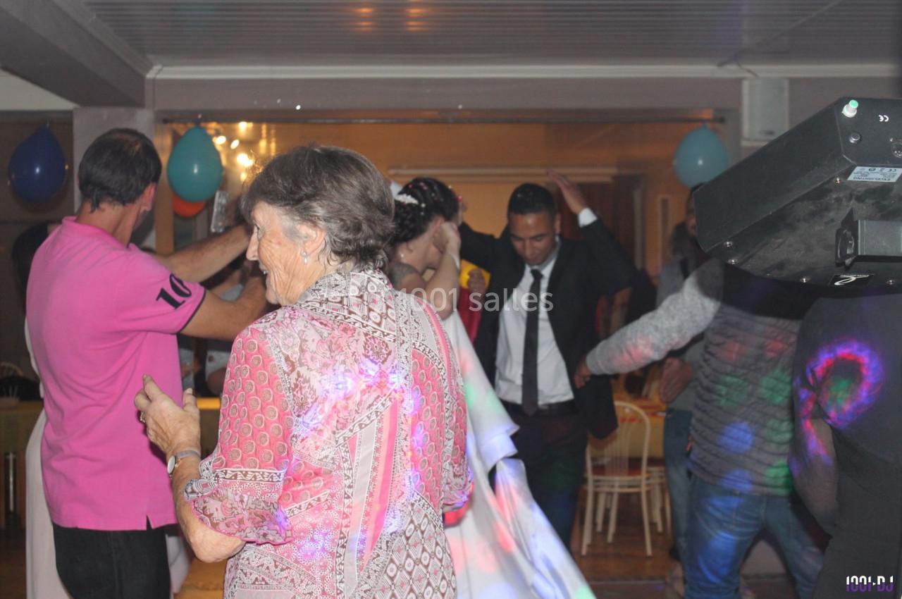 Des personnes dansent dans une salle éclairée, décorée de ballons, lors d'un événement festif.