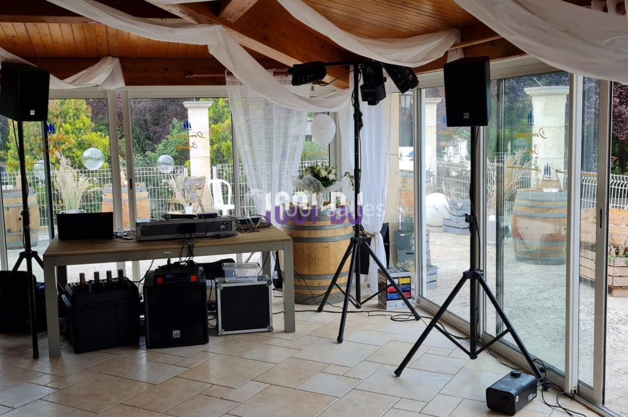 Salle lumineuse avec équipement audio installé, entourée de baies vitrées donnant sur une terrasse et un jardin.