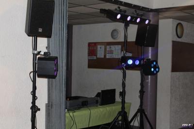 Équipement de sonorisation installé en extérieur sous une tente blanche, entouré de végétation.