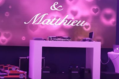 Miniature DJ Saint-Étienne (Loire) - Ruby Events #18 Salle de réception décorée avec des lumières violettes, tables dressées et écran affichant des prénoms.