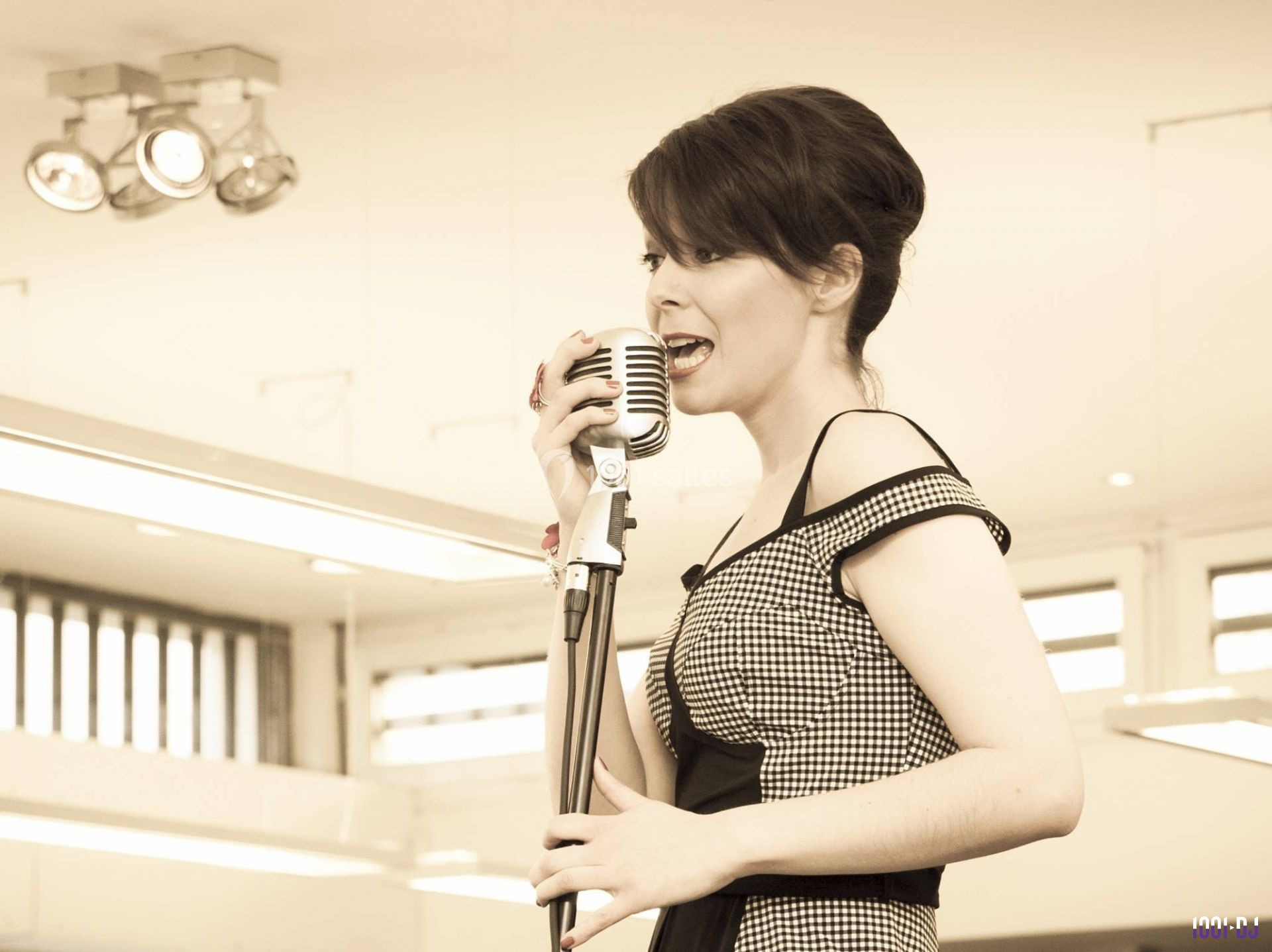 Une femme chante dans un microphone vintage dans un intérieur lumineux.