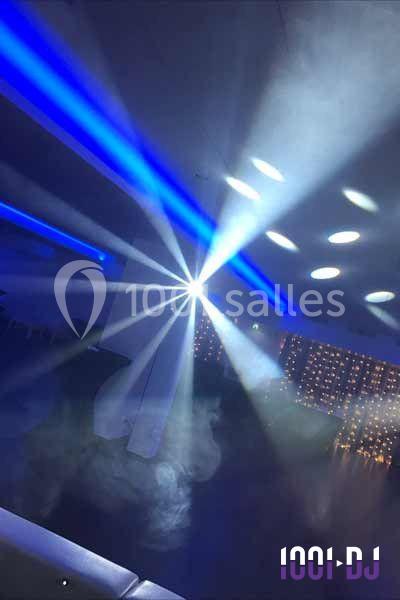 Jeux de lumières colorées et fumée dans une salle sombre, créant une ambiance festive.