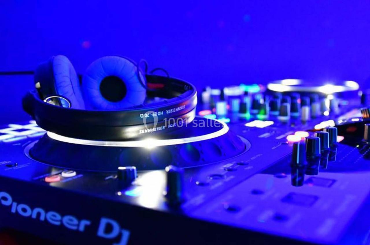 Table de mixage avec casque audio posé dessus, éclairée par des lumières bleues dans un environnement sombre.