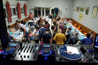 Homme en chemise rouge décorée, utilisant une table de mixage avec un ordinateur en arrière-plan, décorations festives…