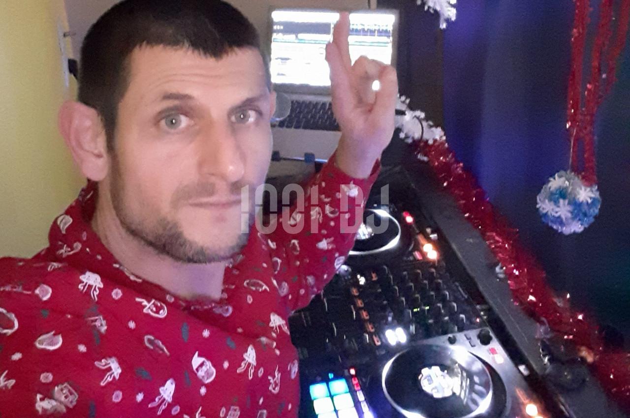 Homme en chemise rouge décorée, utilisant une table de mixage avec un ordinateur en arrière-plan, décorations festives…