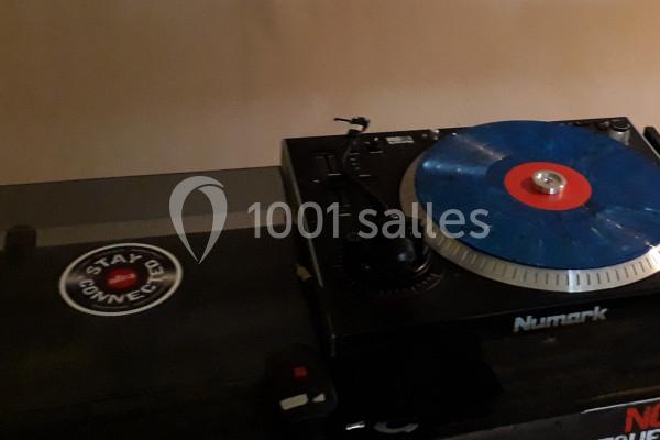 Platine vinyle noire avec un disque bleu et rouge en lecture, posée sur une table sombre.