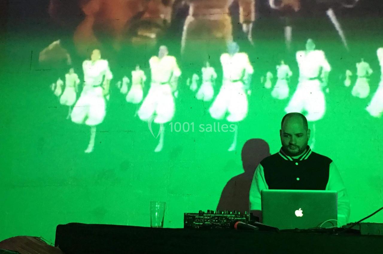 Un DJ mixe sur son ordinateur devant une projection murale d'images colorées et animées.