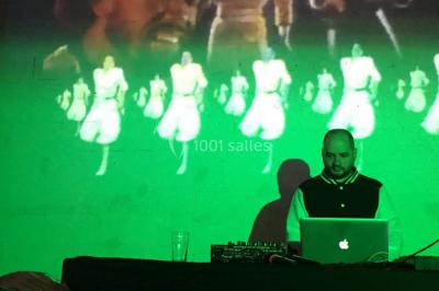 Des personnes dansent sous un abri décoré de ballons et guirlandes lumineuses, dans une ambiance festive nocturne.