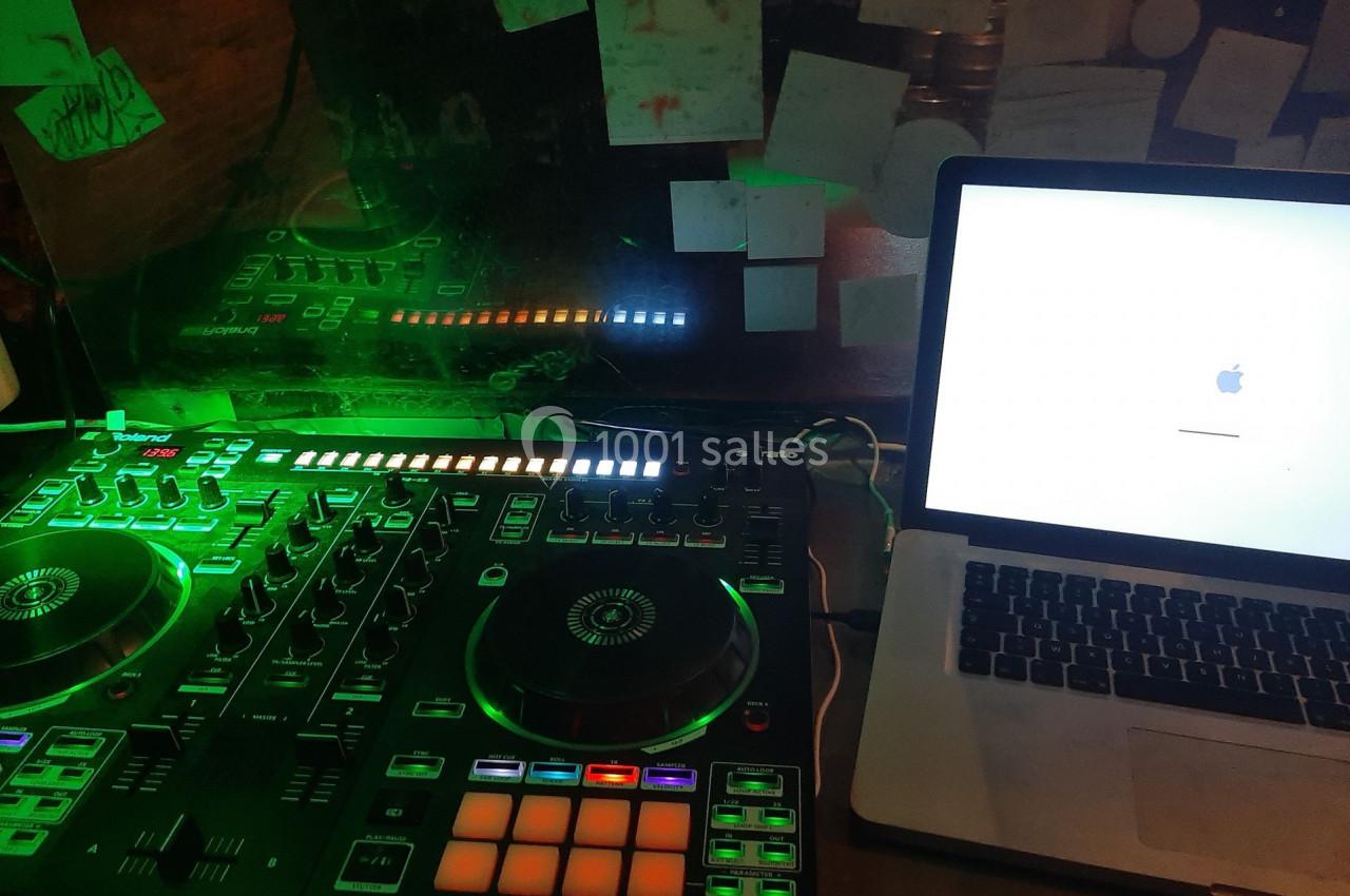 Table de mixage éclairée en vert à côté d'un ordinateur portable affichant un écran de démarrage Apple.