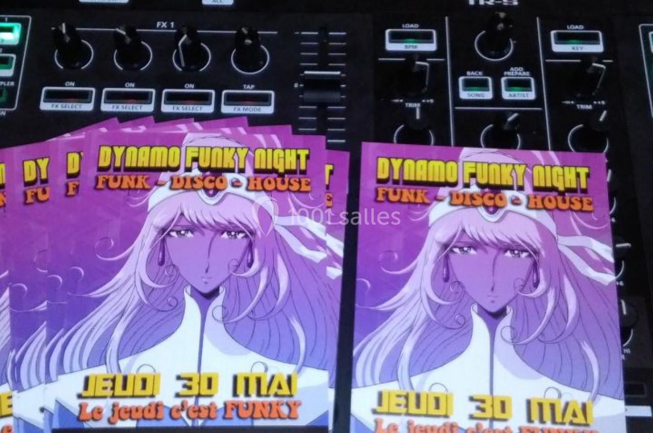 Deux flyers colorés pour une soirée musicale posés sur une table de mixage avec des CD en arrière-plan.