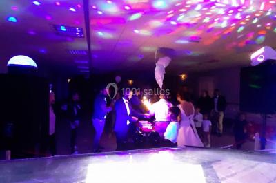 Des personnes dansent sous un abri décoré de ballons et guirlandes lumineuses, dans une ambiance festive nocturne.