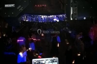 Des personnes dansent sous des lumières colorées dans une ambiance festive et tamisée.