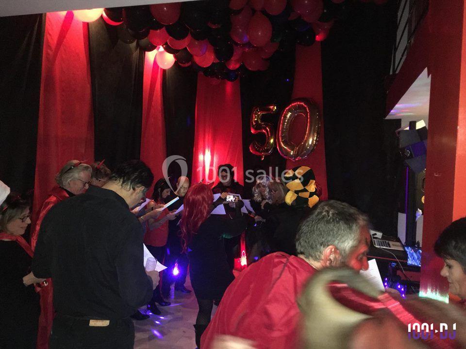 Des personnes déguisées participent à une fête d'anniversaire avec des ballons noirs et rouges et le chiffre 50 en…