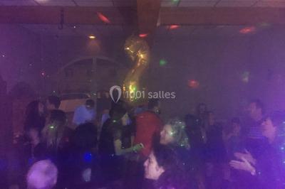 Des personnes dansent sous des lumières colorées dans une ambiance festive et tamisée.