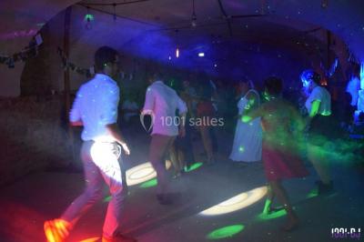 Des personnes dansent sous des lumières colorées dans une ambiance festive et tamisée.